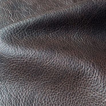 Close-up of textured dark brown leather fabric with visible grain and folds.