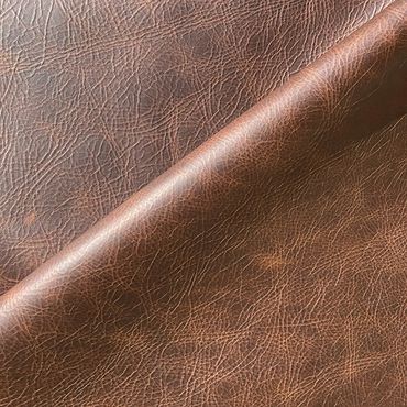 Close-up of textured brown leather fabric with natural creases.
