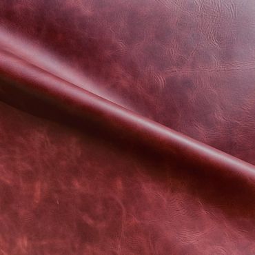 Close-up of textured reddish-brown leather fabric with a fold.