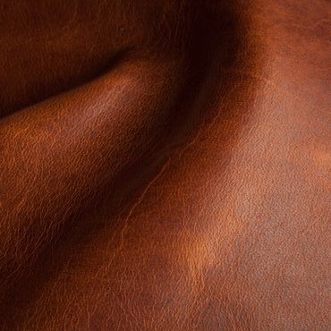 Close-up of textured brown leather surface with natural wrinkles.