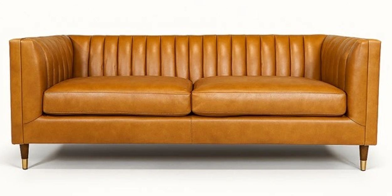 Modern caramel leather sofa with vertical stitching and wooden legs.