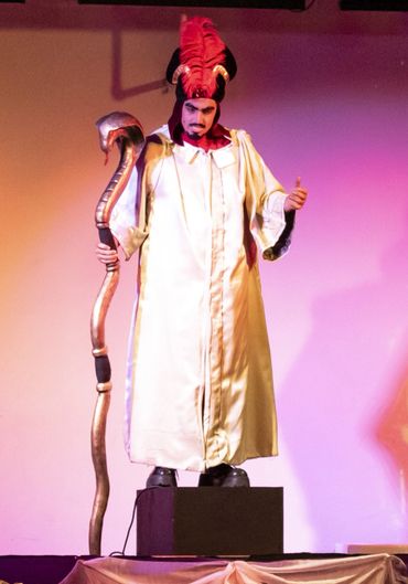 A person dressed as Jafar from Aladdin holding a snake staff on stage.