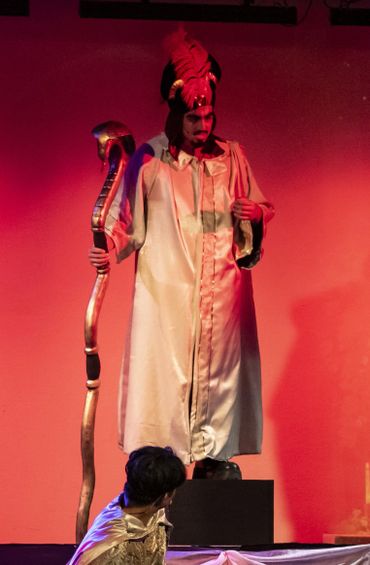 Actor in a fantasy costume holding a staff shaped like a snake's head.