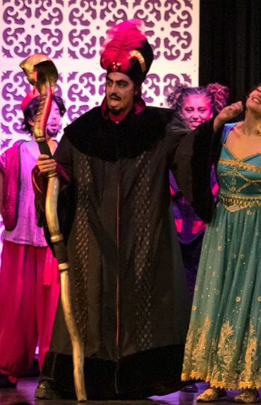 Actors in colorful costumes perform a scene from a theatrical play.