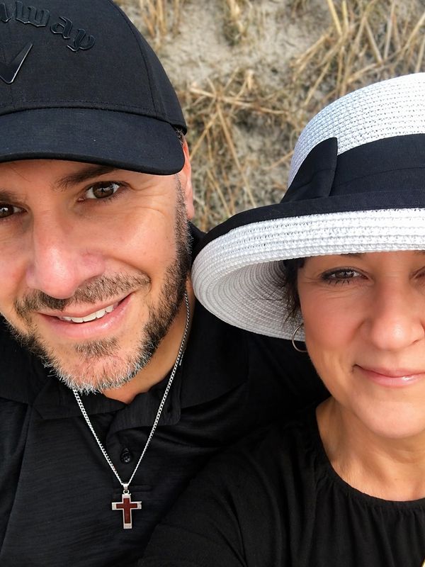 Smiling couple wearing hats outdoors in a close-up selfie.
