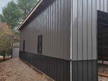 Newly constructed metal building with black and gray panels and small windows.