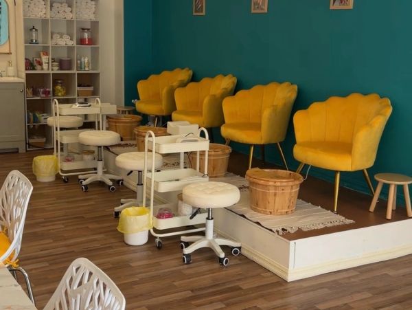 Cozy nail salon seating with yellow chairs and wooden accents.