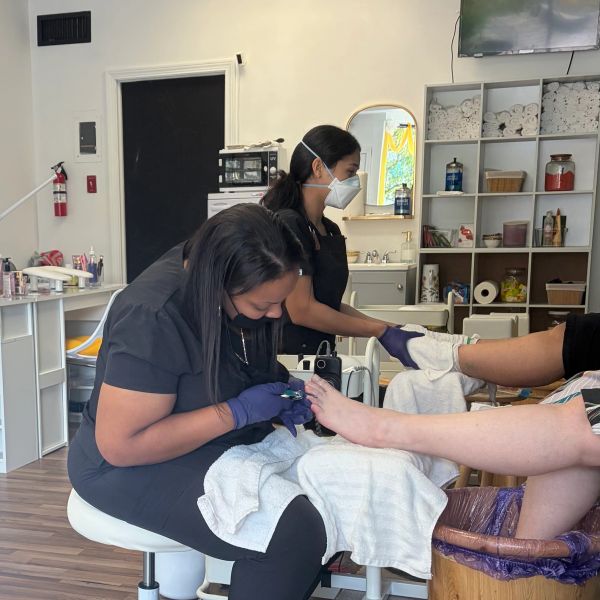 A pedicure session in a salon with two workers and a customer.