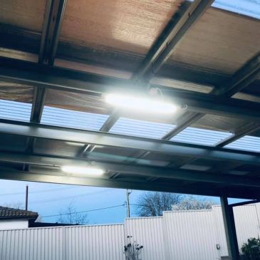 Illuminated lights under a metal roof with a blue sky background.