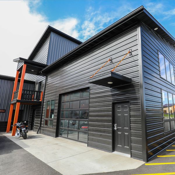 Modern black metal building with large windows and motorcycle outside.