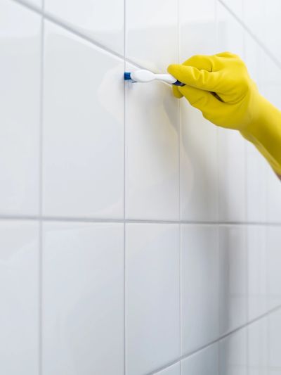 BD365 meticulously cleaning tiles and grout with a toothbrush