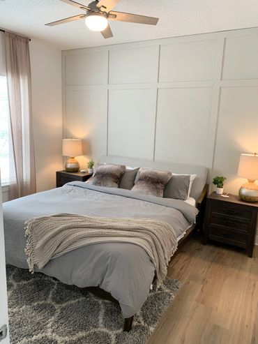 Modern bedroom with gray bedding, wooden nightstands, and soft lighting.
