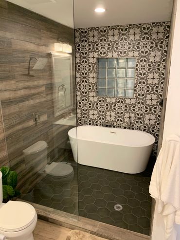 Modern bathroom with a freestanding bathtub and patterned tile wall.