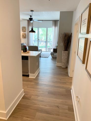 Modern apartment hallway leading to a bright living room with balcony.