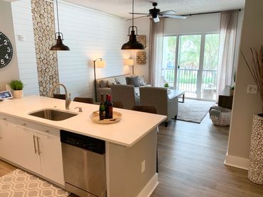 Modern kitchen and living room with white island and cozy seating area.