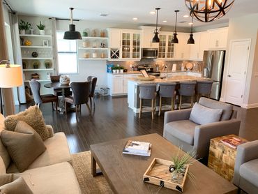 Modern open-concept living room and kitchen with neutral tones and cozy seating.