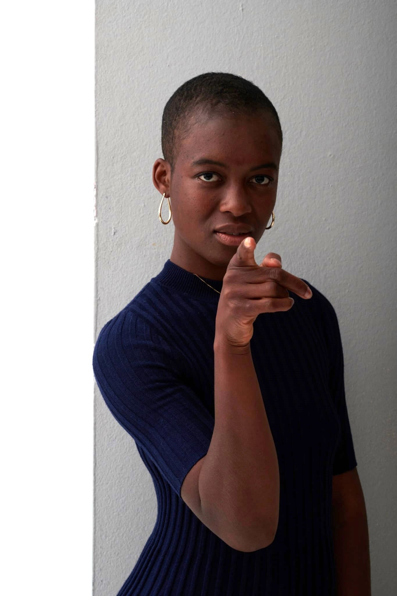Mentorin für Mütter Essenam Enaku, mit Kurzhaarfrisur zeigt mit dem Zeigefinger auf dich. EXIT