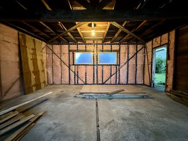 An unfinished garage with insulation covered by a vapor barrier and tape by home repair