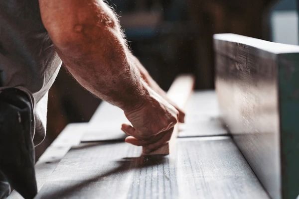 A person smoothing wood on a table with their hands.
