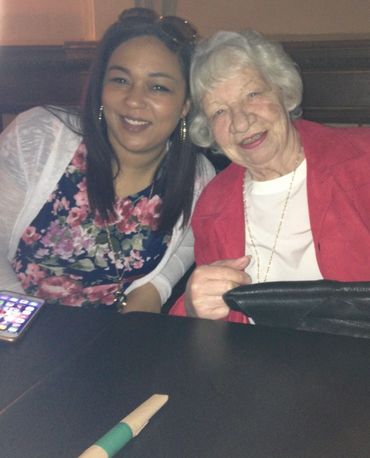 A young woman and an elderly woman smiling together at a table.