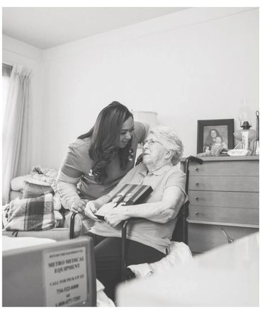 Caregiver warmly interacting with elderly woman in wheelchair.
