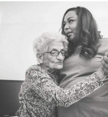 An elderly woman embraces a younger woman in a tender moment.