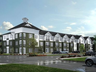Modern three-story apartment building with green and white exterior and multiple balconies.