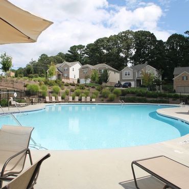A serene outdoor swimming pool surrounded by lounge chairs and umbrellas in a residential area.