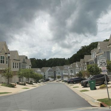 Suburban street with modern houses under cloudy skies.
