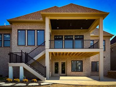 Newly built modern brick house with a spacious covered balcony and stairs.