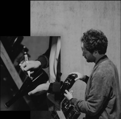 Man signing black bottles with a marker pen.