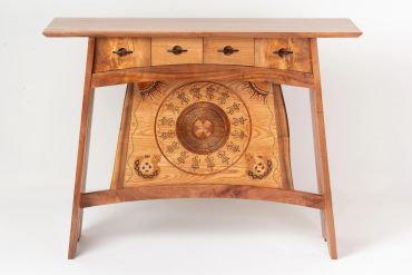 Wooden desk with intricate carvings and four drawers.