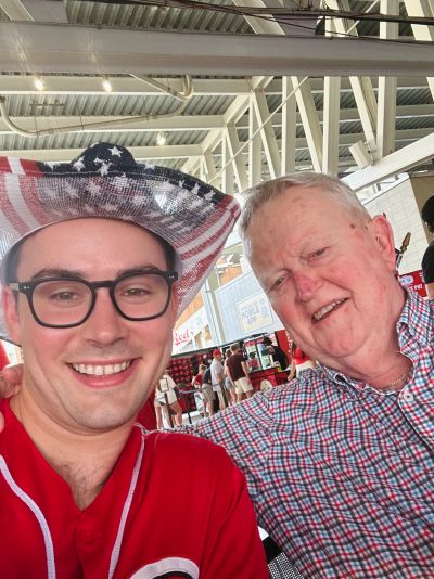 Two men smiling, one wearing a patriotic hat.