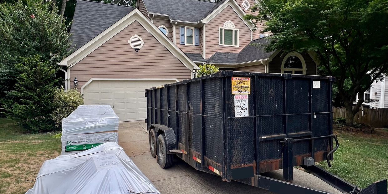 Large black dumpster on driveway of house.