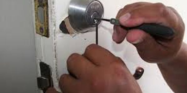 Close-up of hands picking a door lock with tools.