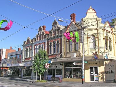 Victorian-style shopfronts on a sunny street with hanging decorations.
