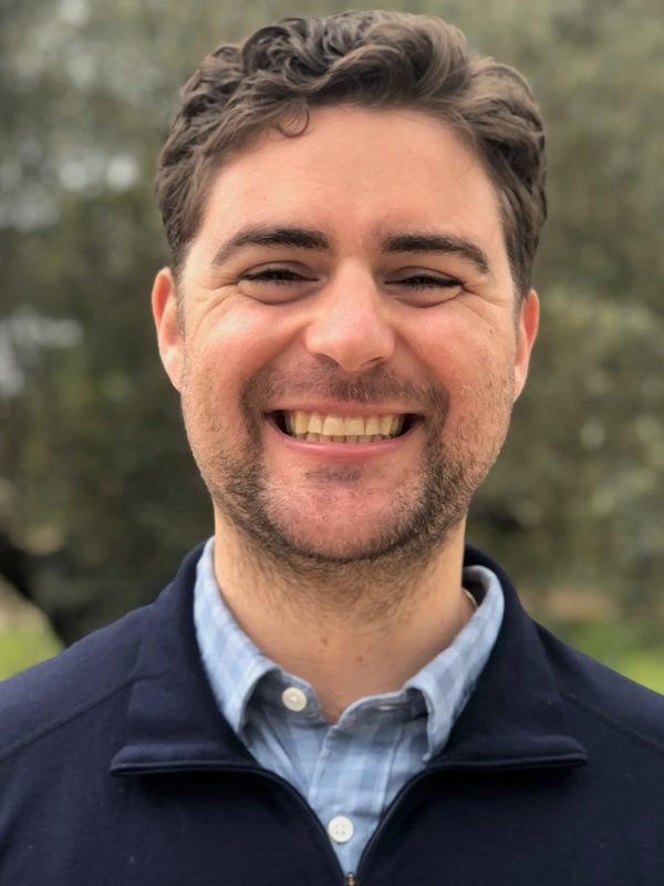 Smiling man outdoors with natural background.