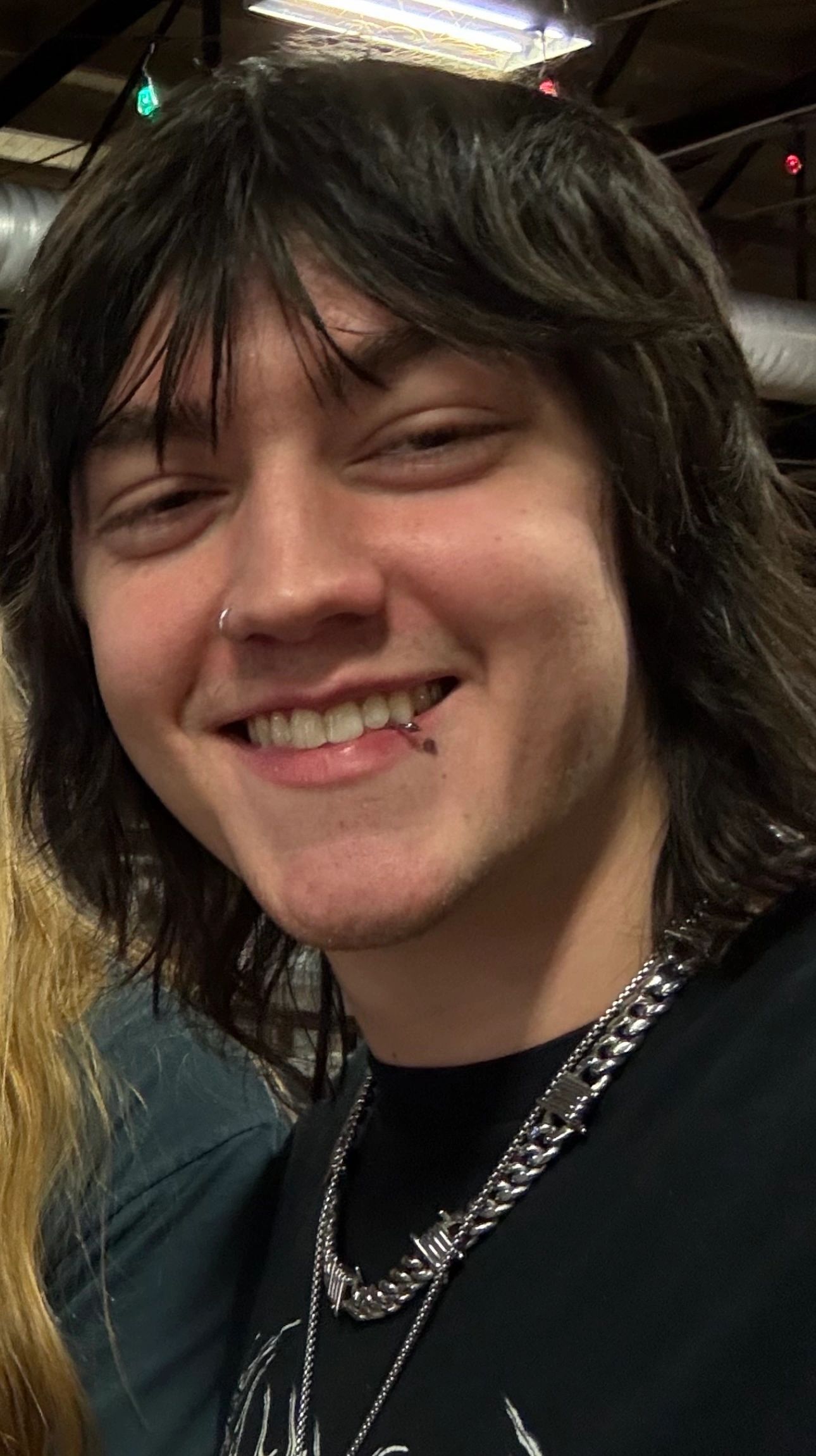 Smiling young man with layered hair and piercings.