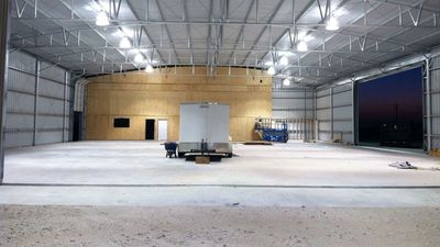Interior of a large, empty warehouse under bright lights.