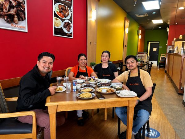 Four people sitting around a table enjoying a meal at Rice Craving restaurant.