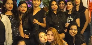 Group of women posing together at an outdoor night event.