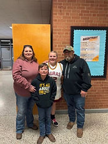 A family of four smiling inside a building with brick walls.