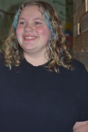 Smiling person with curly hair wearing a black shirt.