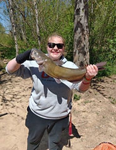 Person proudly holding a large fish caught outdoors.