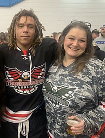 Two people smiling together at a sports event, wearing team jerseys.