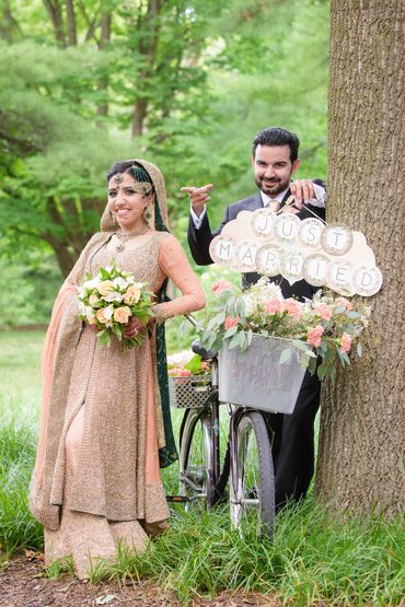 Bride and Groom outdoors by decorated bicycle with a just married sign