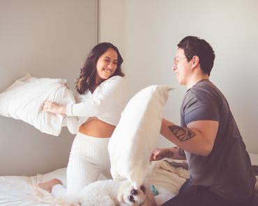 Happy Couple pillow fighting on bed