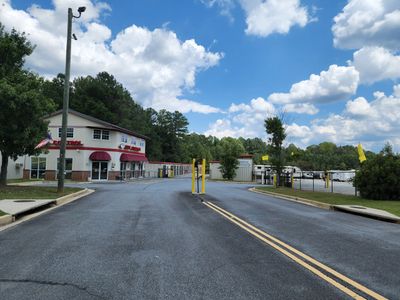 Self storage facility entrance with a clear sky and yellow flags.