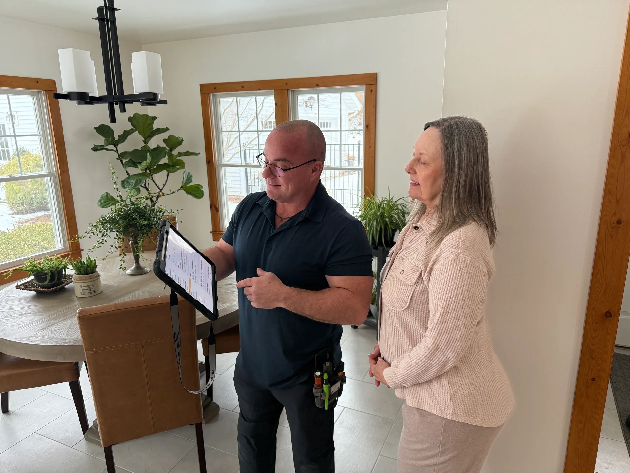 Man explaining information on a tablet to a woman in a bright dining area.