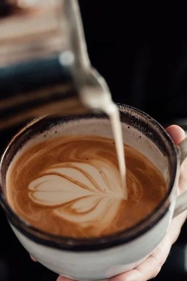 Pouring milk into coffee to create latte art.